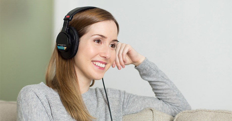 Young woman smiling sitting on a couch with headphones on